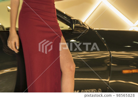 Beautiful thighs removed from a woman's dress standing next to a car 98565828