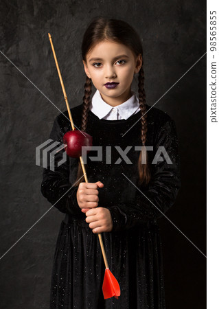 A girl with pigtails holds an arrow aimed at an apple A girl with pigtails holds an arrow aimed at an apple 98565855