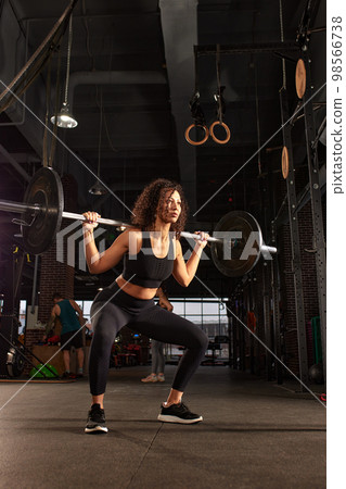 Athletic african american woman getting ready to do barbell squat in crossfit gym, hard workout. 98566738