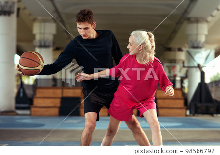 Diversity guy and girl playing basketball on the city playground Diversity guy and girl playing basketball on the city playground 98566792