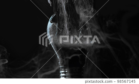Lamp explosion smoke cloud. Power failure. Defocused gray color vapor haze in broken glass light bulb on dark black night abstract background. Lamp explosion smoke cloud. Power failure. Defocused gray color vapor haze in broken glass light bulb on dark black night abstract background. 98567145