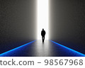 The silhouette of a man walking towards a bright light in the opened huge wall. A light in the end of a tunnel. The concept of success, freedom of choice, open mind, meditation. 98567968