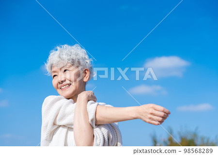 Senior woman stretching under the blue sky Senior woman stretching under the blue sky 98568289
