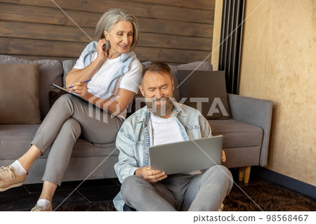 Man and woman searching something online on their devices Man and woman searching something online on their devices 98568467