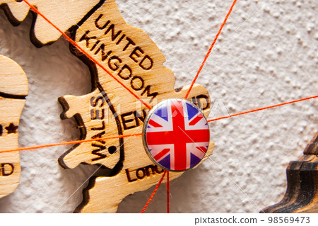 United Kindom flag on the pushpin with red thread showed the paths of movement or areas of influence in the global economy on the wooden map. Planning of traveling or logistic concept. Network United Kindom flag on the pushpin with red thread showed the paths of movement or areas of influence in the global economy on the wooden map. Planning of traveling or logistic concept. Network 98569473
