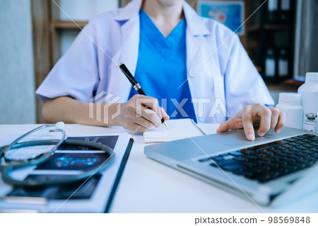 Medical technology concept. Doctor working with mobile phone and stethoscope and digital tablet laptop in modern office at hospital in morning light. 98569848
