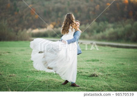 Wedding couple on the nature is hugging each other. Beautiful model girl in white dress. Man in suit Wedding couple on the nature is hugging each other. Beautiful model girl in white dress. Man in suit 98570539