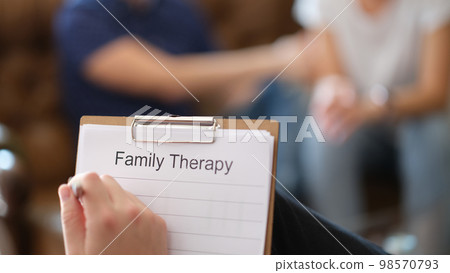 Psychologist writes in his notebook while analyzing couple's discussion about family relationships. 98570793