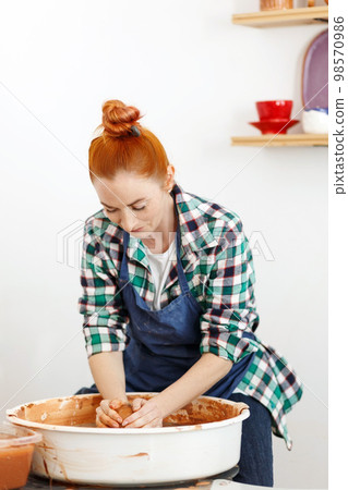 Happy female sculptor making clay pot on pottery wheel Happy female sculptor making clay pot on pottery wheel 98570986