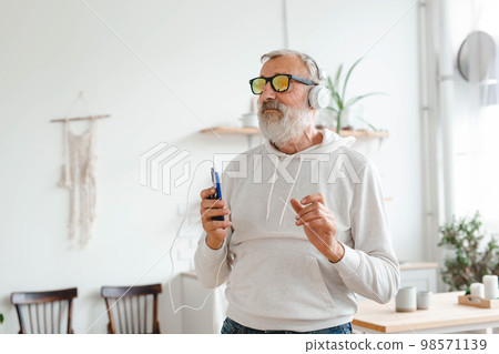 Happy senior man dancing while listening to music with headphones copy space and empty place for advertising - active old people and enjoyment dance mood Happy senior man dancing while listening to music with headphones copy space and empty place for advertising - active old people and enjoyment dance mood 98571139