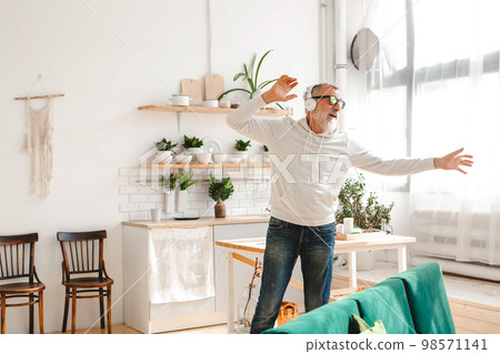 Senior man dance and using smartphone app for creating playlist music on mobile app - Elderly male having fun dancing with mobile phone technology - Tech and joyful elderly lifestyle concept 98571141