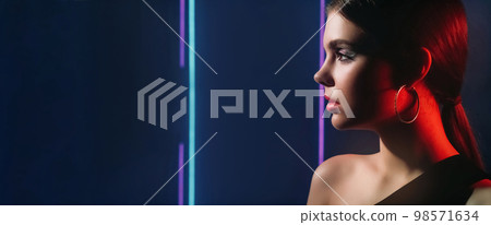 90s fashion. Neon beauty. Retro disco look. Red purple blue color light profile portrait of teen girl model face with party makeup on dark empty space background. 98571634