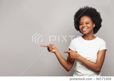 Happy nice brunette woman pointing finger on white studio wall banner background with copy space Happy nice brunette woman pointing finger on white studio wall banner background with copy space 98571808