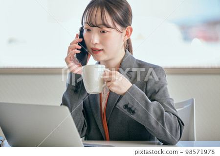 年輕女子在她的辦公桌前打電話 98571978