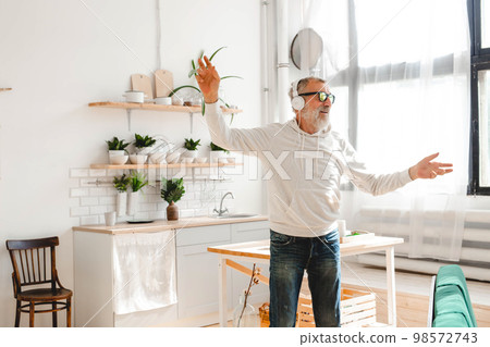 Happy senior man dancing while listening to music with headphones - active old people and enjoyment dance mood 98572743