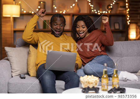 Emotional african american couple gambling on Internet 98573356