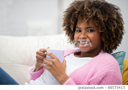 Happy african american woman chillng at home, drinking coffee Happy african american woman chillng at home, drinking coffee 98573413