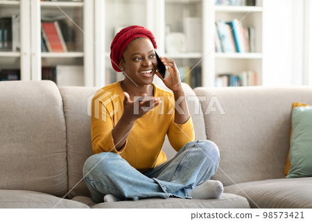 Relaxed candid young african american woman talking on phone Relaxed candid young african american woman talking on phone 98573421