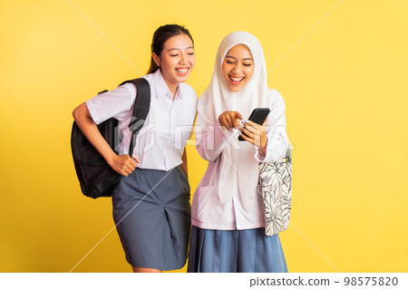 two high school girls excited while using mobile phone 98575820