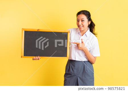 girl in uniform holding blackboard beside her with finger pointing girl in uniform holding blackboard beside her with finger pointing 98575821