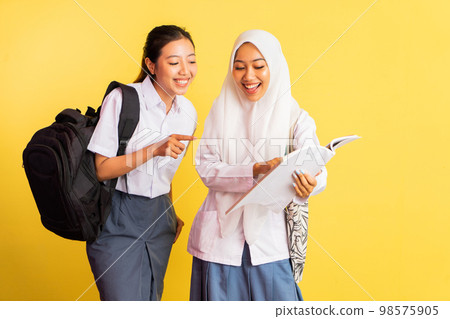 two high school girls opening books while carrying bags two high school girls opening books while carrying bags 98575905