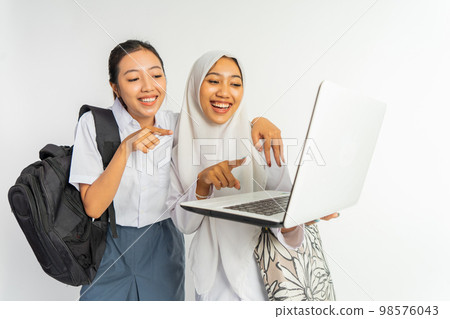 two smiling vocational high school girls while using a laptop 98576043