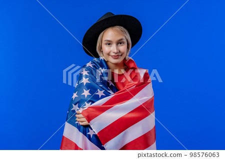 Smiling woman with national USA flag on blue background. American patriot 98576063