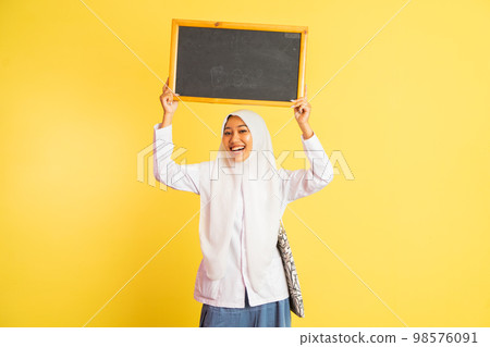 girl in school uniform in veil carrying black chalkboard up girl in school uniform in veil carrying black chalkboard up 98576091