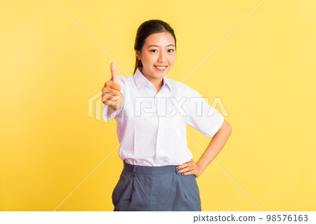 teenage girl in high school uniform standing with thumbs up 98576163