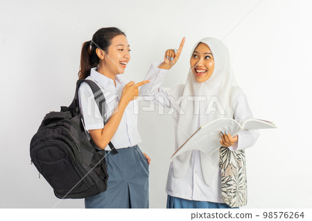 two laughing vocational high school girls carrying bags while chatting two laughing vocational high school girls carrying bags while chatting 98576264