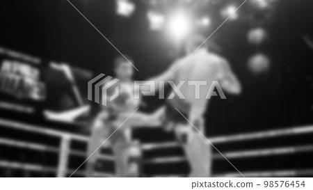 Blurred images black and white photo style of Thai boxing or Muay Thai or Kickboxing which local and foriegn boxer are fighting on the ring at indoor stage as martial art sport. Muay Thai Kick boxing 98576454