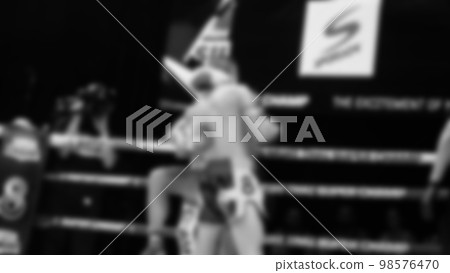 Blurred images black and white photo style of Thai boxing or Muay Thai or Kickboxing which local and foriegn boxer are fighting on the ring at indoor stage as martial art sport. Muay Thai Kick boxing 98576470
