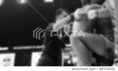 Blurred images black and white photo style of Thai boxing or Muay Thai or Kickboxing which local and foriegn boxer are fighting on the ring at indoor stage as martial art sport. Muay Thai Kick boxing 98576482