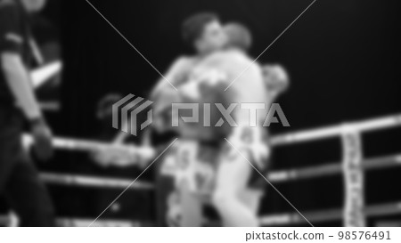 Blurred images black and white photo style of Thai boxing or Muay Thai or Kickboxing which local and foriegn boxer are fighting on the ring at indoor stage as martial art sport. Muay Thai Kick boxing 98576491