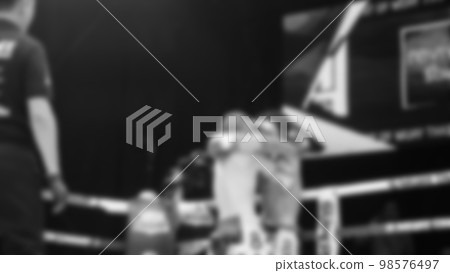Blurred images black and white photo style of Thai boxing or Muay Thai or Kickboxing which local and foriegn boxer are fighting on the ring at indoor stage as martial art sport. Muay Thai Kick boxing 98576497