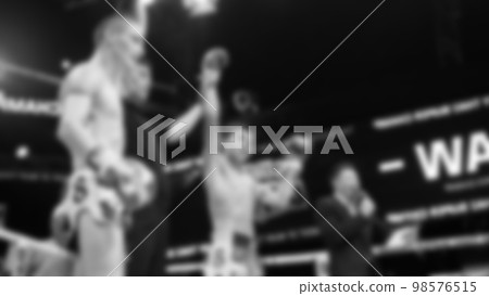 Blurred images black and white photo style of Thai boxing or Muay Thai or Kickboxing which local and foriegn boxer are fighting on the ring at indoor stage as martial art sport. Muay Thai Kick boxing 98576515