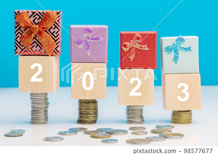 Four stacks of coins, on which there are cubes with the inscription 2023 and gift boxes on top. 98577677