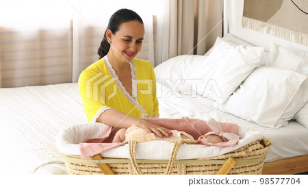 Happy young mother watching her cute baby girl sleep in the crib 98577704