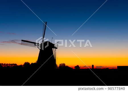 Windmills in the Netherlands. Historic buildings. Agriculture. Summer landscape during sunset. 98577840