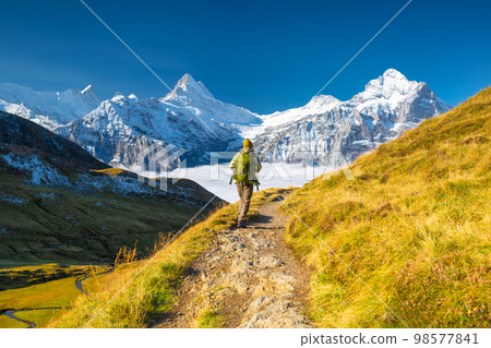 A mountain hiker with a backpack against the backdrop of a mountain panorama. 98577841