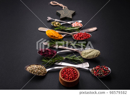 Composition consisting of a variation of spices in metal spoons laid out in the shape of a Christmas tree 98579382