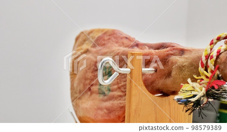 A front leg of Serrano ham mapped on a wooden stand on a white background. 98579389