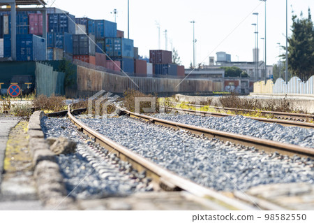 Train railways near the warehouse with a bunch of containers in the open air Train railways near the warehouse with a bunch of containers in the open air 98582550