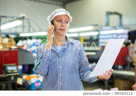 Fruit sorting factory forewoman with papers talking on phone Fruit sorting factory forewoman with papers talking on phone 98583513