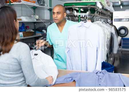 Laundry employee handing out clean clothes to client 98583575