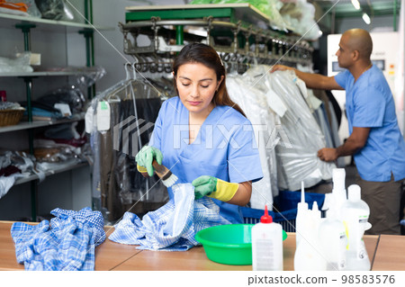 Focused woman drycleaner removing spots and stains 98583576