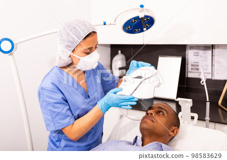 Man receiving facial light therapy in aesthetic medicine office 98583629