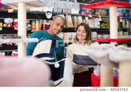 Woman and man choosing different accessories for their pets in pet store Woman and man choosing different accessories for their pets in pet store 98583783