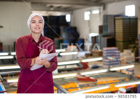 Young female supervisor with papers inspecting mandarins sorting workshop Young female supervisor with papers inspecting mandarins sorting workshop 98583795