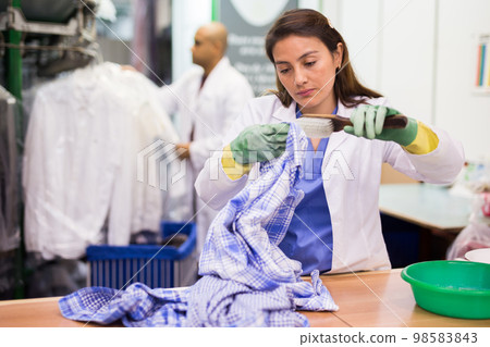 Focused woman drycleaner removing spots and stains Focused woman drycleaner removing spots and stains 98583843